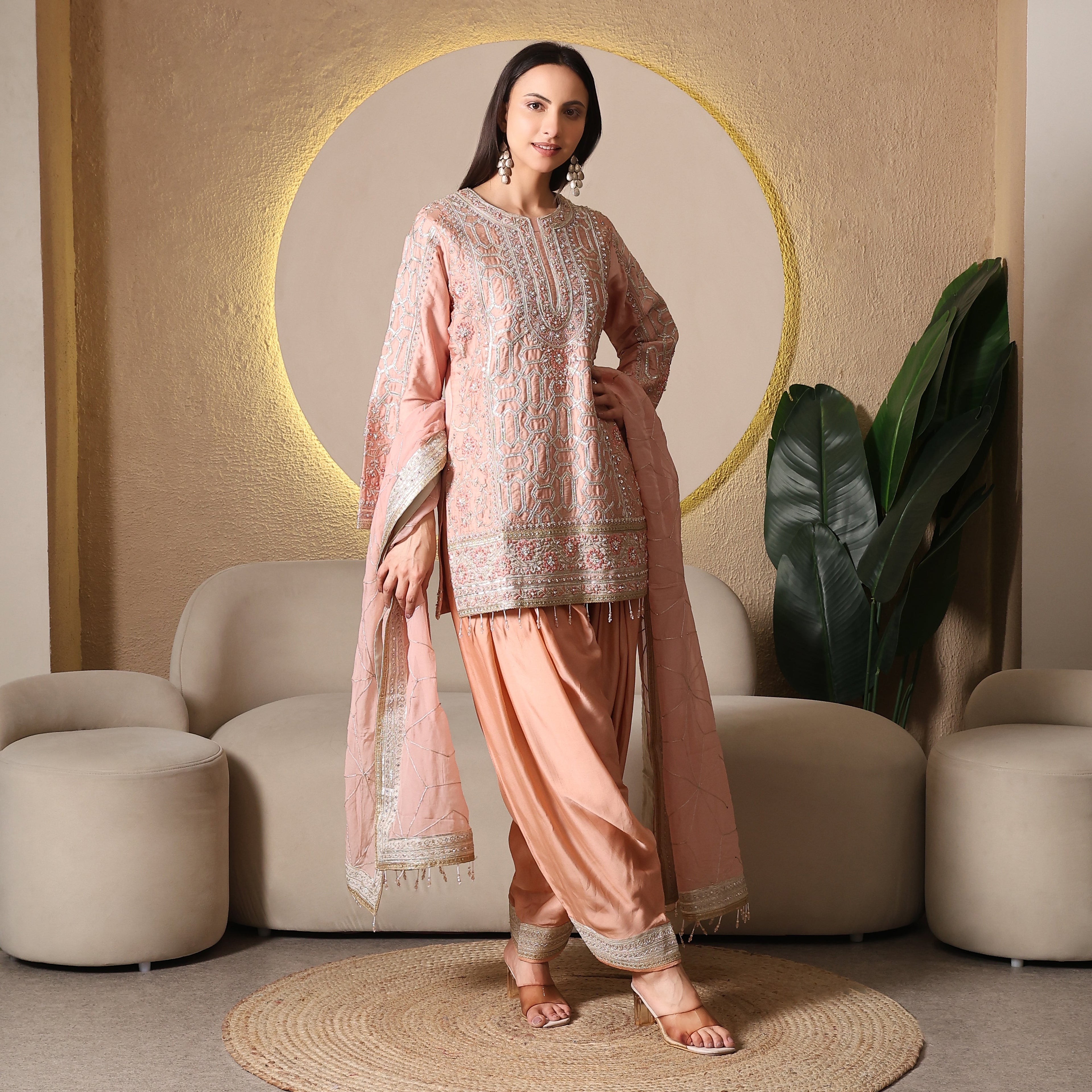 Woman wearing embroidered peach ethnic suit with dupatta, ideal for festive occasions