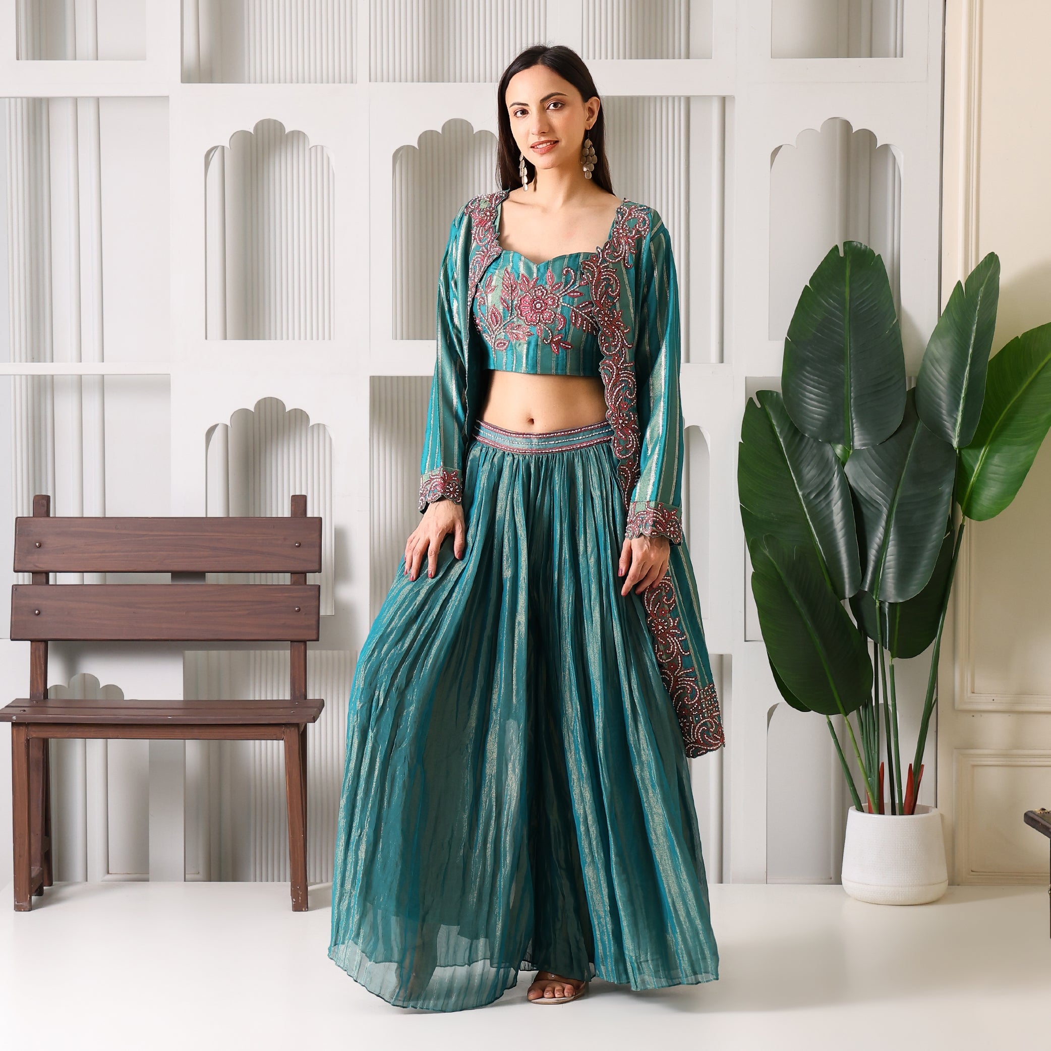 Woman wearing teal Banarasi ethnic suit with embroidered blouse and long flared skirt indoors