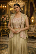 Woman in a gold embroidered ethnic Anarkali suit with dupatta, posing in a luxurious setting