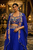 Woman in royal blue embroidered ethnic Anarkali suit with floral detailing, chandbali earrings, and elegant background lighting, ideal for festive or wedding wear.