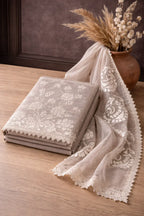 Beige embroidered Banarasi fabric with floral lace detailing, styled with a rustic vase.