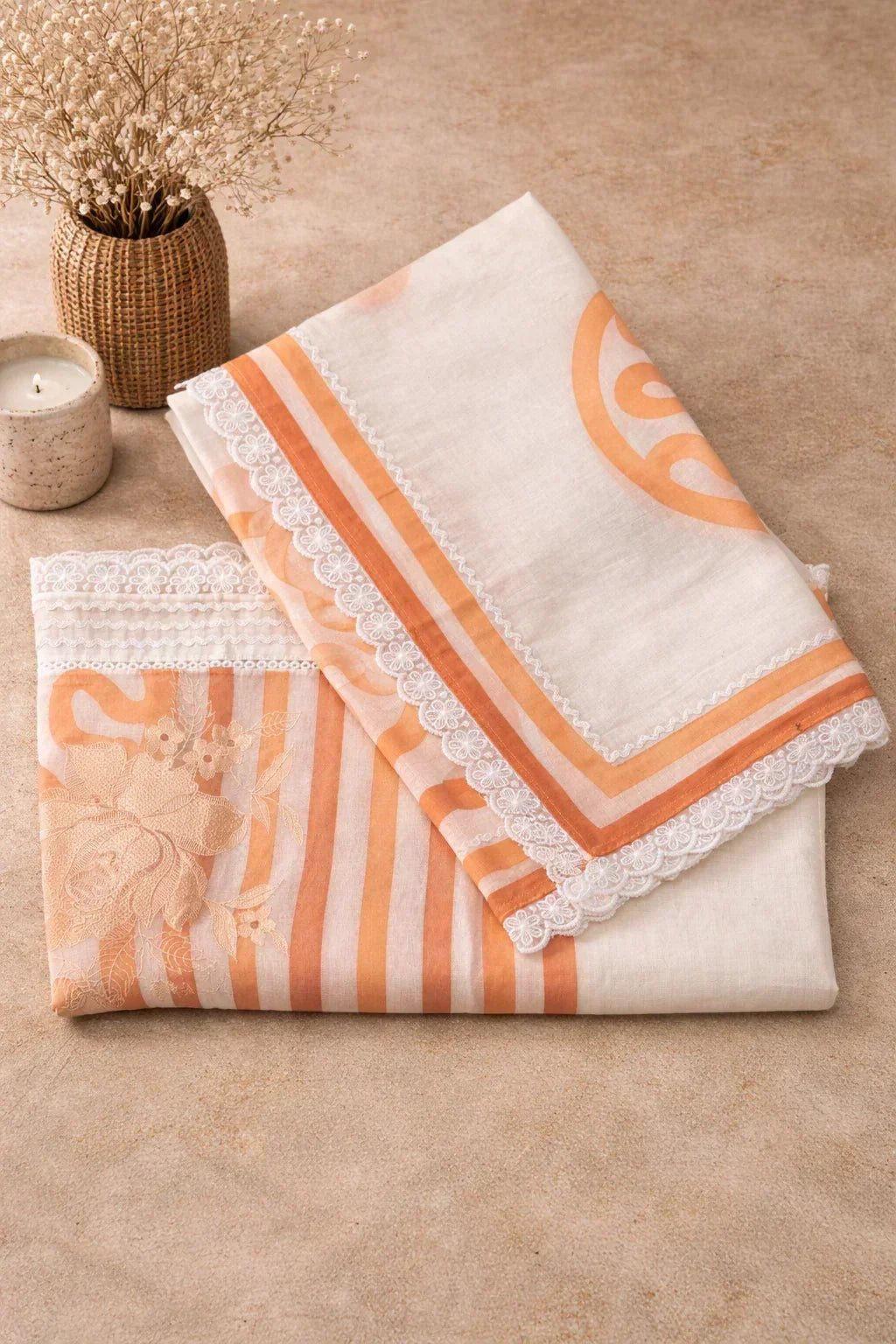 Peach and white ethnic fabric with floral embroidery and lace border, arranged flat on beige surface