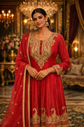 Woman in red Banarasi Anarkali suit with gold embroidery, festive ethnic wear indoors