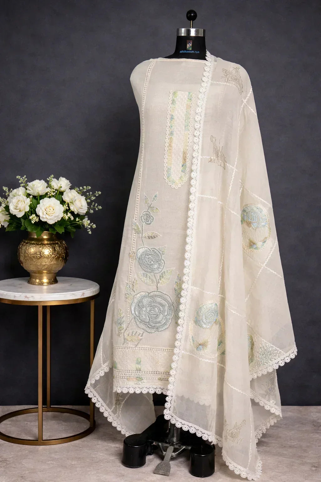 Ivory ethnic suit with pastel floral embroidery and lace details, displayed on mannequin