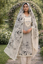 Woman in floral embroidered Anarkali suit with dupatta, standing in a garden archway