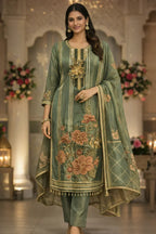 Woman in sage green embroidered Anarkali suit with floral patterns, dupatta, and jewelry