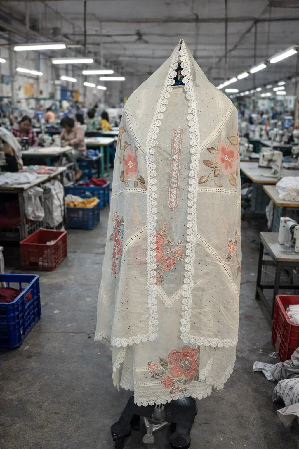 Ivory ethnic suit with floral embroidery and lace trim displayed in textile workshop
