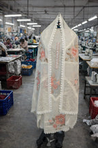 Ivory ethnic suit with floral embroidery and lace trim displayed in textile workshop