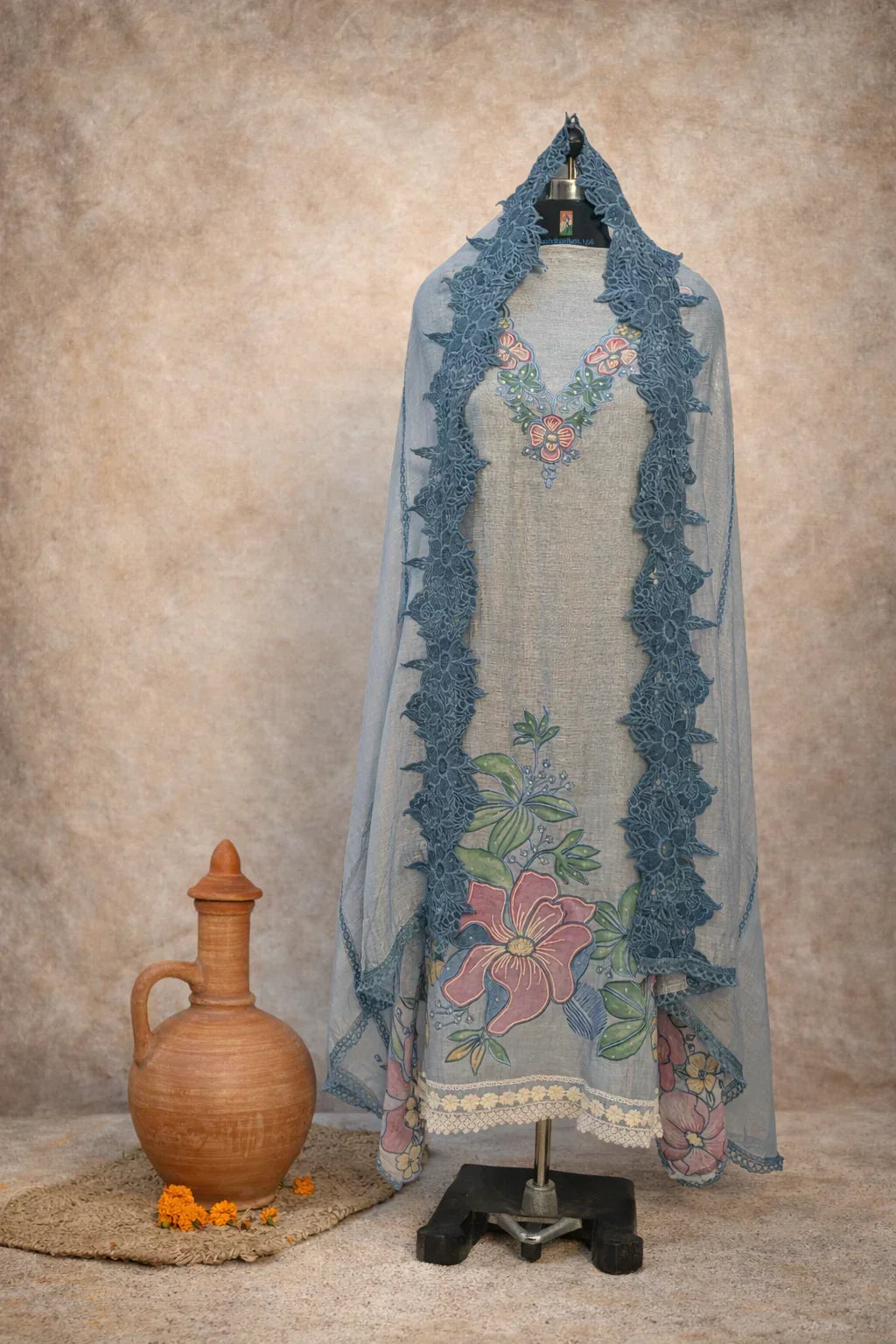 Blue floral embroidered ethnic suit set with dupatta on mannequin, clay pot beside