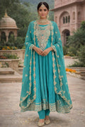 Woman in teal Banarasi Anarkali suit with gold embroidery, traditional jewelry, outdoor setting