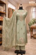 Pastel green embroidered ethnic suit set with mirror work and sheer dupatta on mannequin