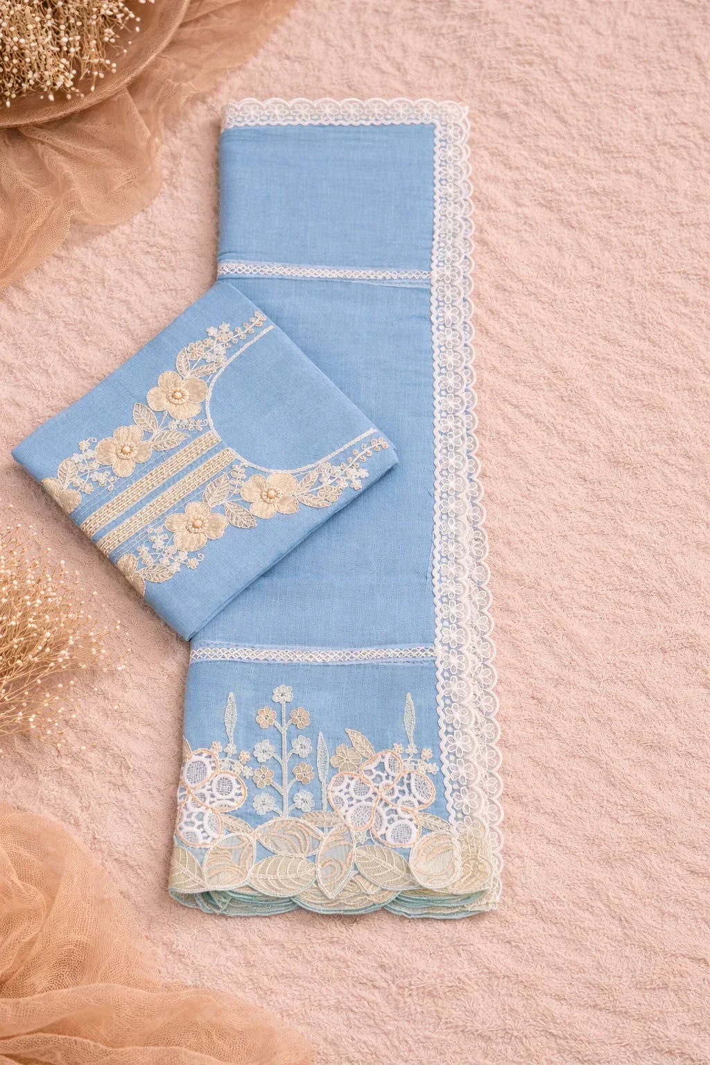 Flat lay of blue ethnic fabric set with floral embroidery and lace, ideal for festive wear.
