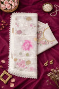 Pastel floral embroidered ethnic fabric with lace border on maroon background, styled with pearls and earrings