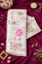 Pastel floral embroidered ethnic fabric with lace border on maroon background, styled with pearls and earrings