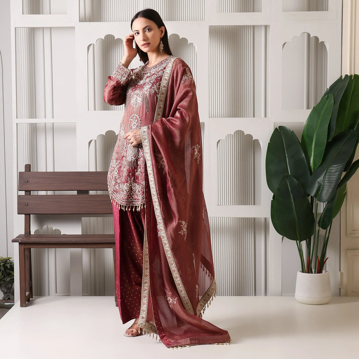 Woman in maroon Banarasi Anarkali suit with dupatta, traditional ethnic wear, indoor setting