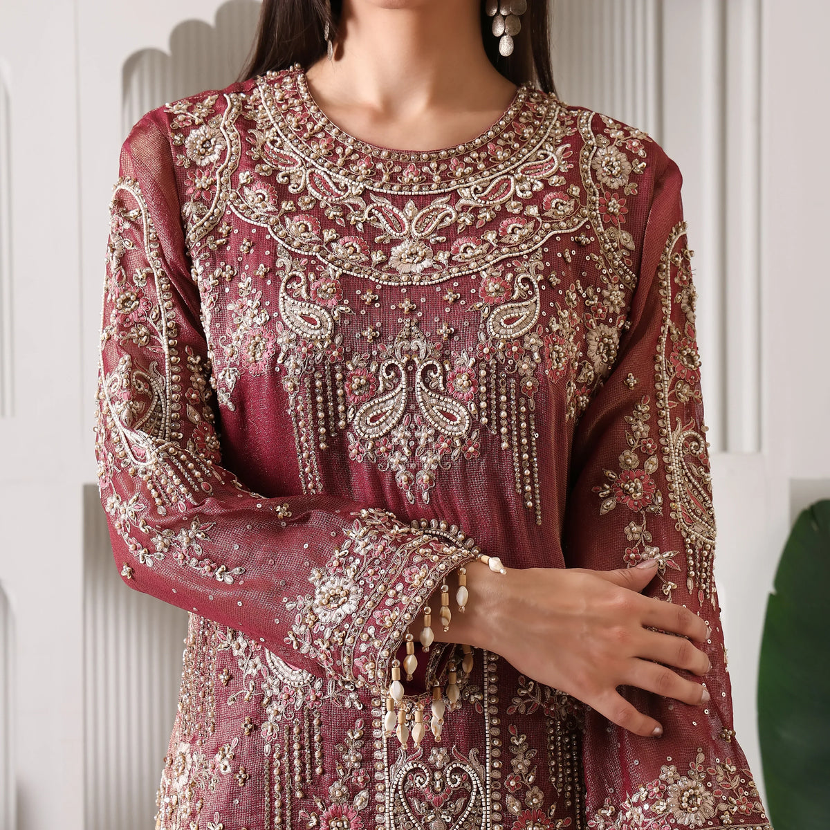 Woman in maroon ethnic suit with intricate embroidery and beadwork, festive wear