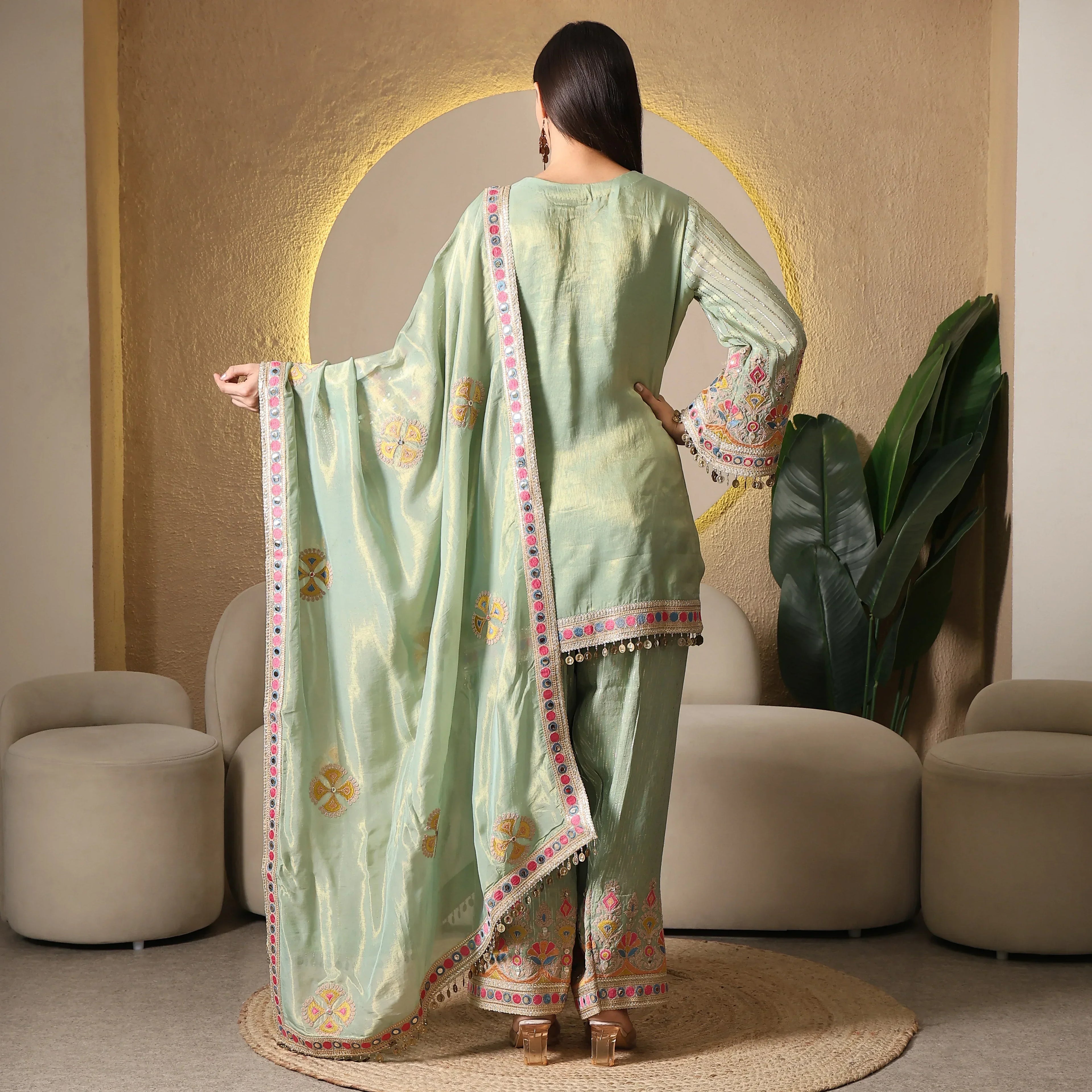 Woman in pastel green embroidered ethnic three-piece suit with dupatta, indoor setting
