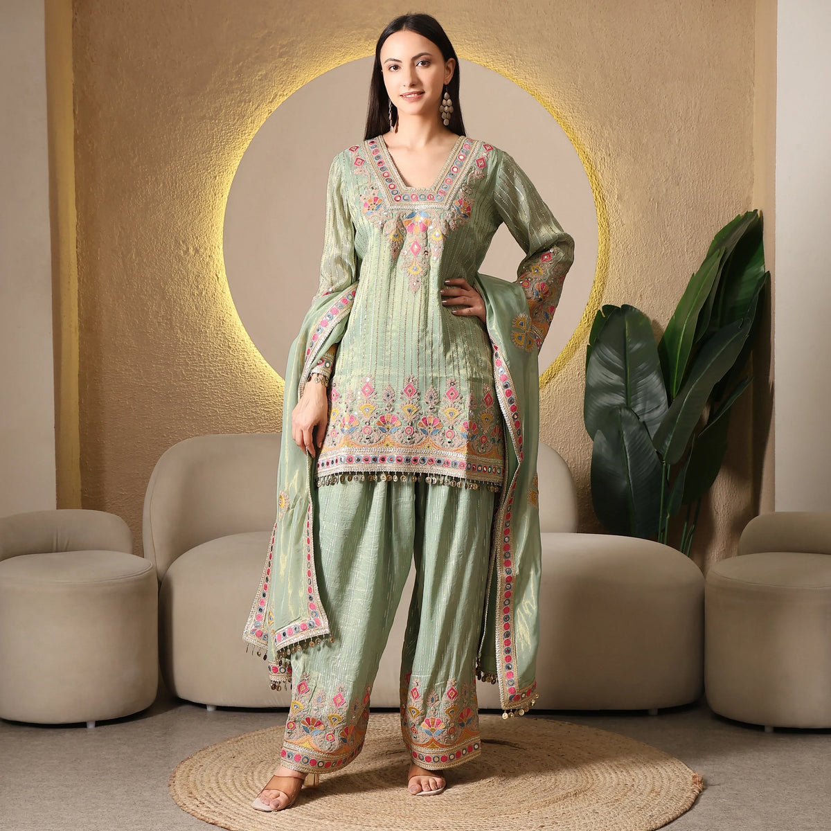 Woman wearing pastel green embroidered ethnic suit with dupatta, festive outfit indoors