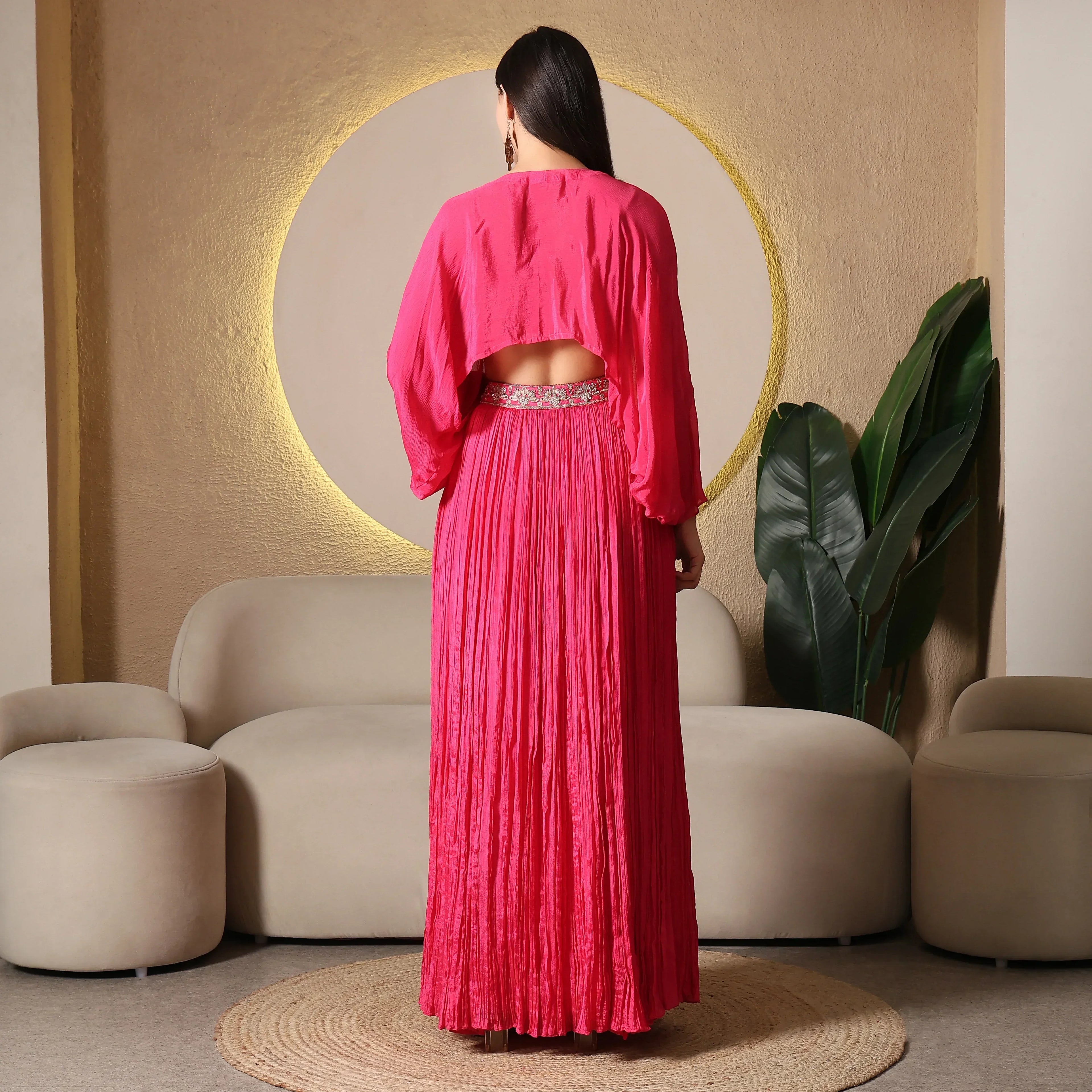 Woman wearing bright pink ethnic Anarkali suit with embellished waistband, back view