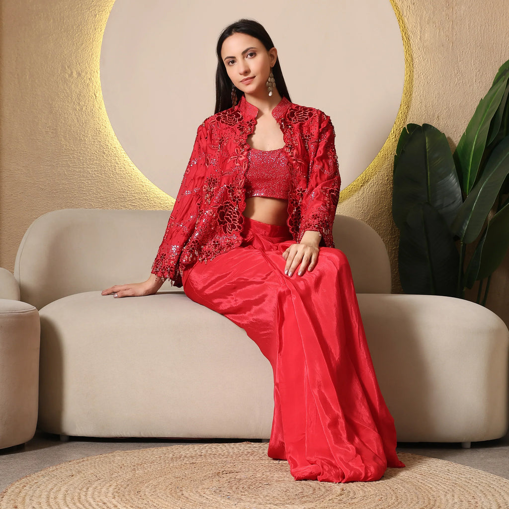 Woman in a red embroidered ethnic jacket set sitting on a beige sofa in a modern room