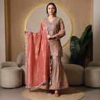 Woman wearing embroidered ethnic suit with flared pants and peach dupatta, festive wear