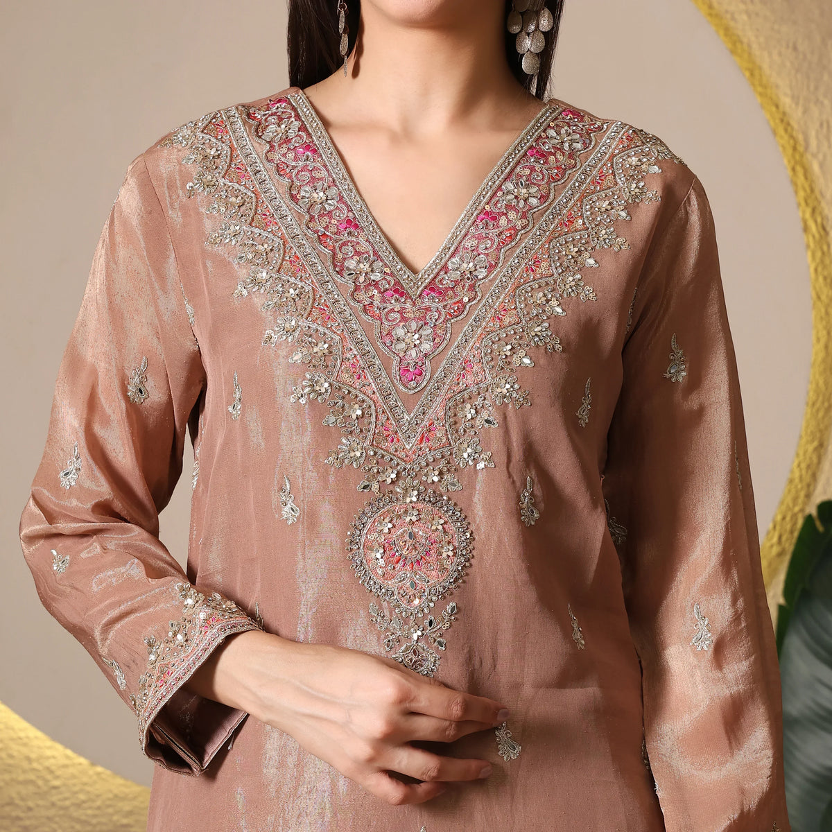Woman wearing a mauve Banarasi ethnic suit with intricate embroidery and sequin detailing