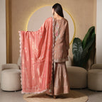 Woman wearing an embroidered ethnic suit with peach dupatta and flared pants, back view