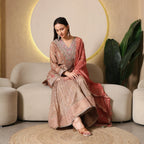 Woman wearing embroidered Banarasi Anarkali suit with dupatta sitting on beige sofa