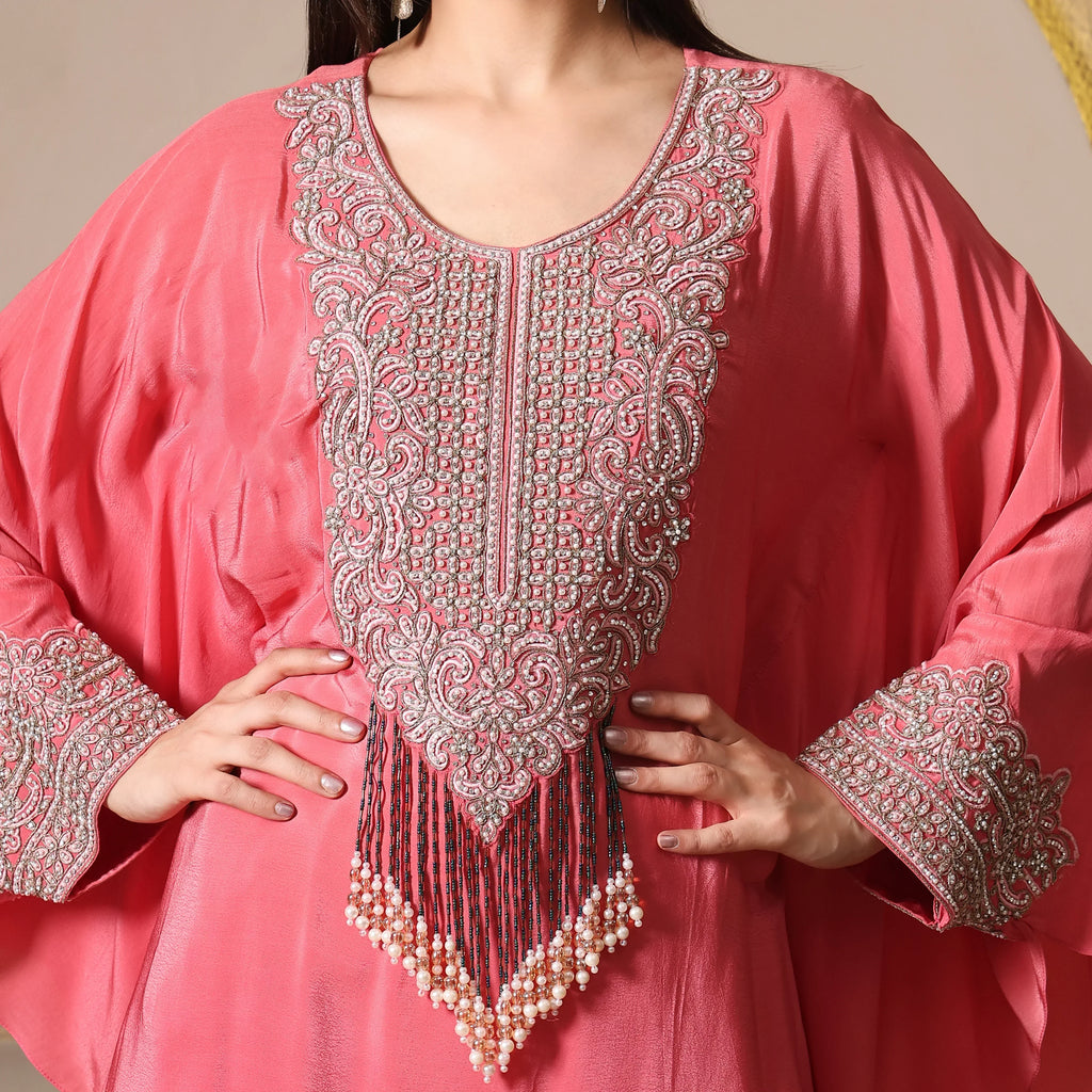 Woman wearing a pink embellished ethnic kurta with intricate beadwork and pearl tassels