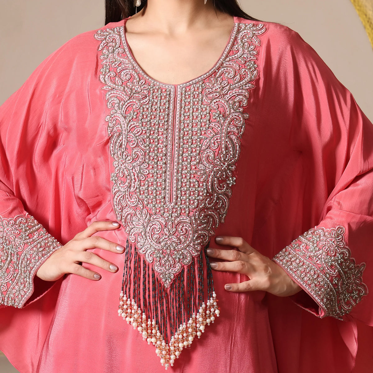 Woman wearing a pink embellished ethnic kurta with intricate beadwork and pearl tassels