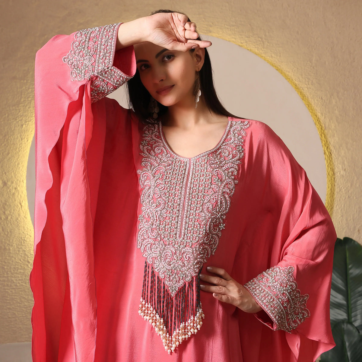 Woman in a pink embroidered ethnic kaftan with beaded detailing and flared sleeves