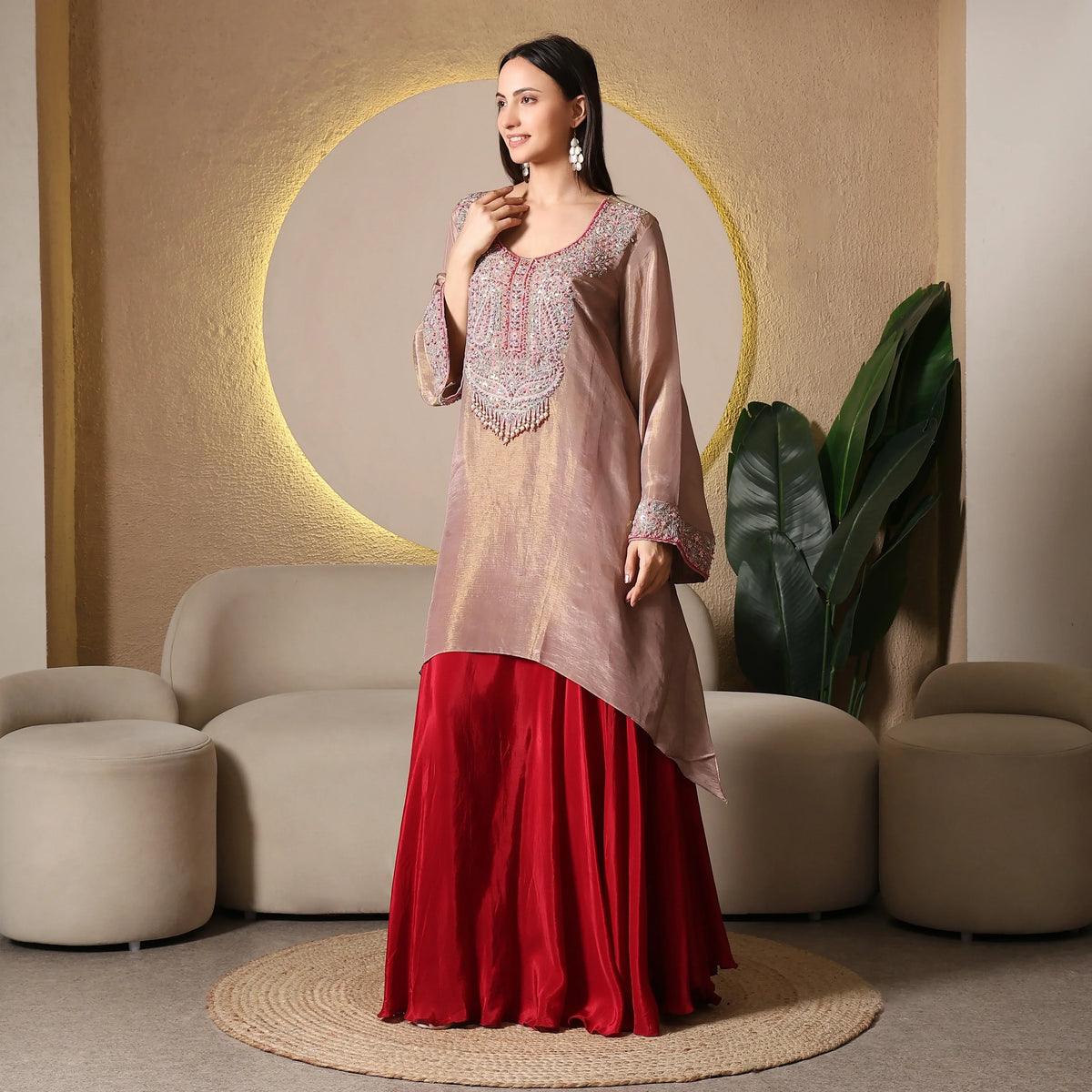 Woman wearing an embroidered kurta with red skirt, posing in a modern ethnic wear setting