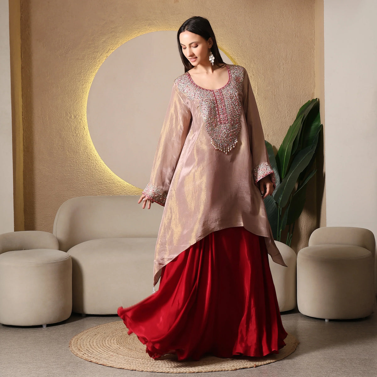 Woman in embroidered kurta and red skirt, luxury ethnic wear in modern living room setting