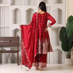 Woman in red embroidered Anarkali suit with dupatta, standing indoors, festive ethnic wear