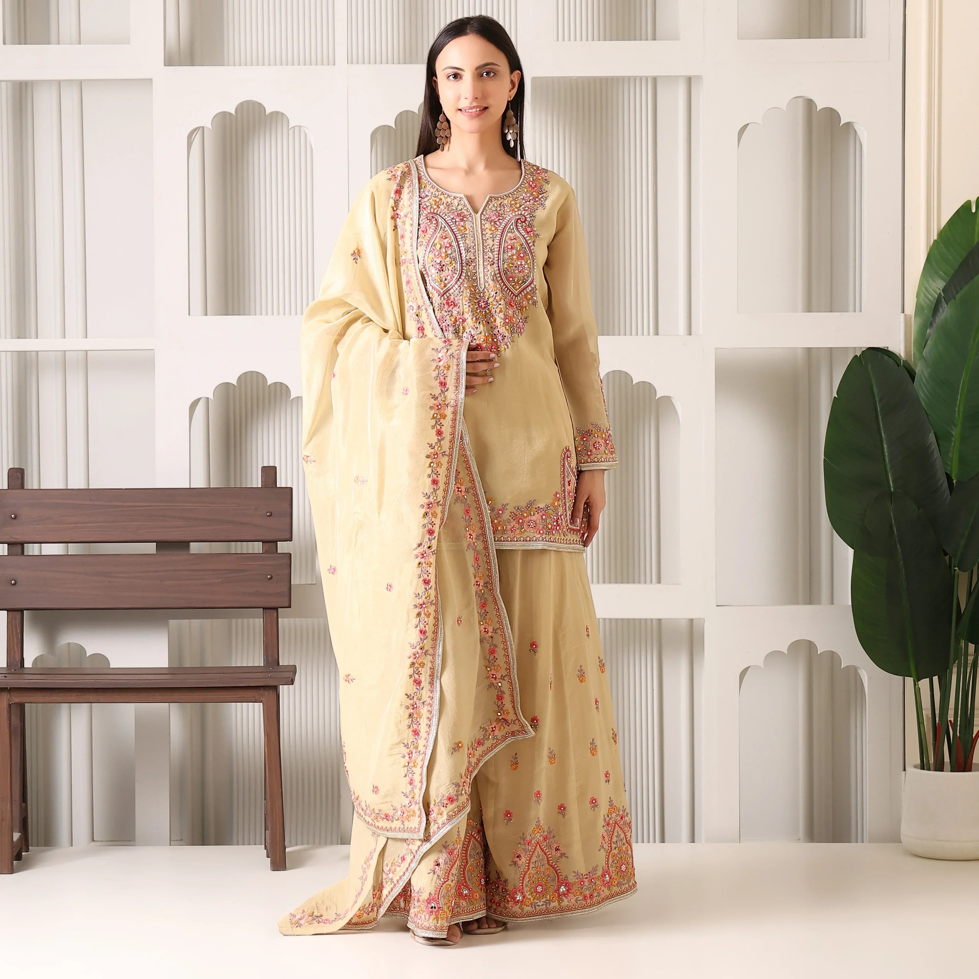 Woman wearing beige Banarasi Anarkali suit with floral embroidery and dupatta indoors