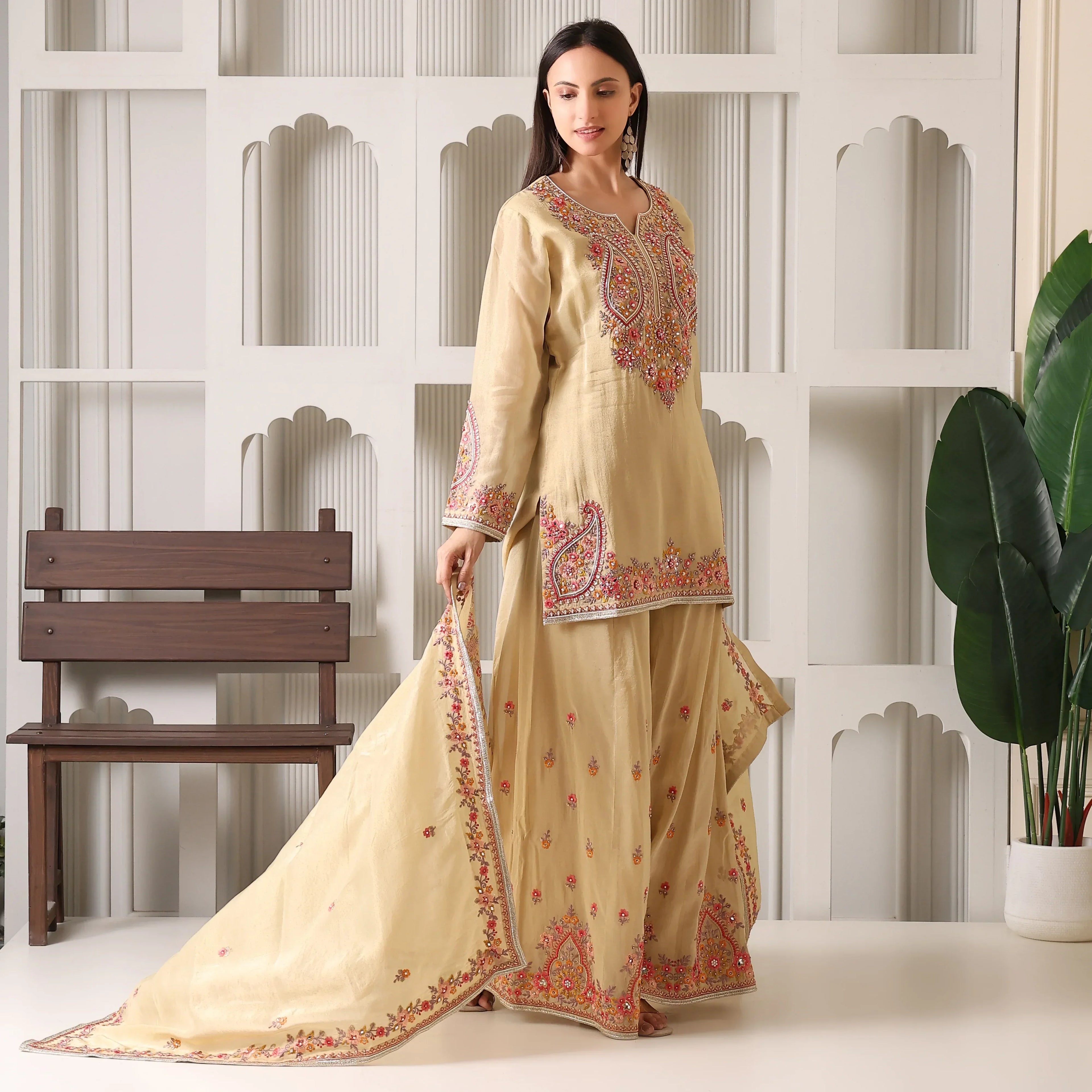 Woman wearing a beige embroidered ethnic suit with dupatta, perfect for weddings or festive wear