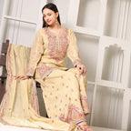 Woman in cream Banarasi Anarkali suit with pink floral embroidery, sitting indoors