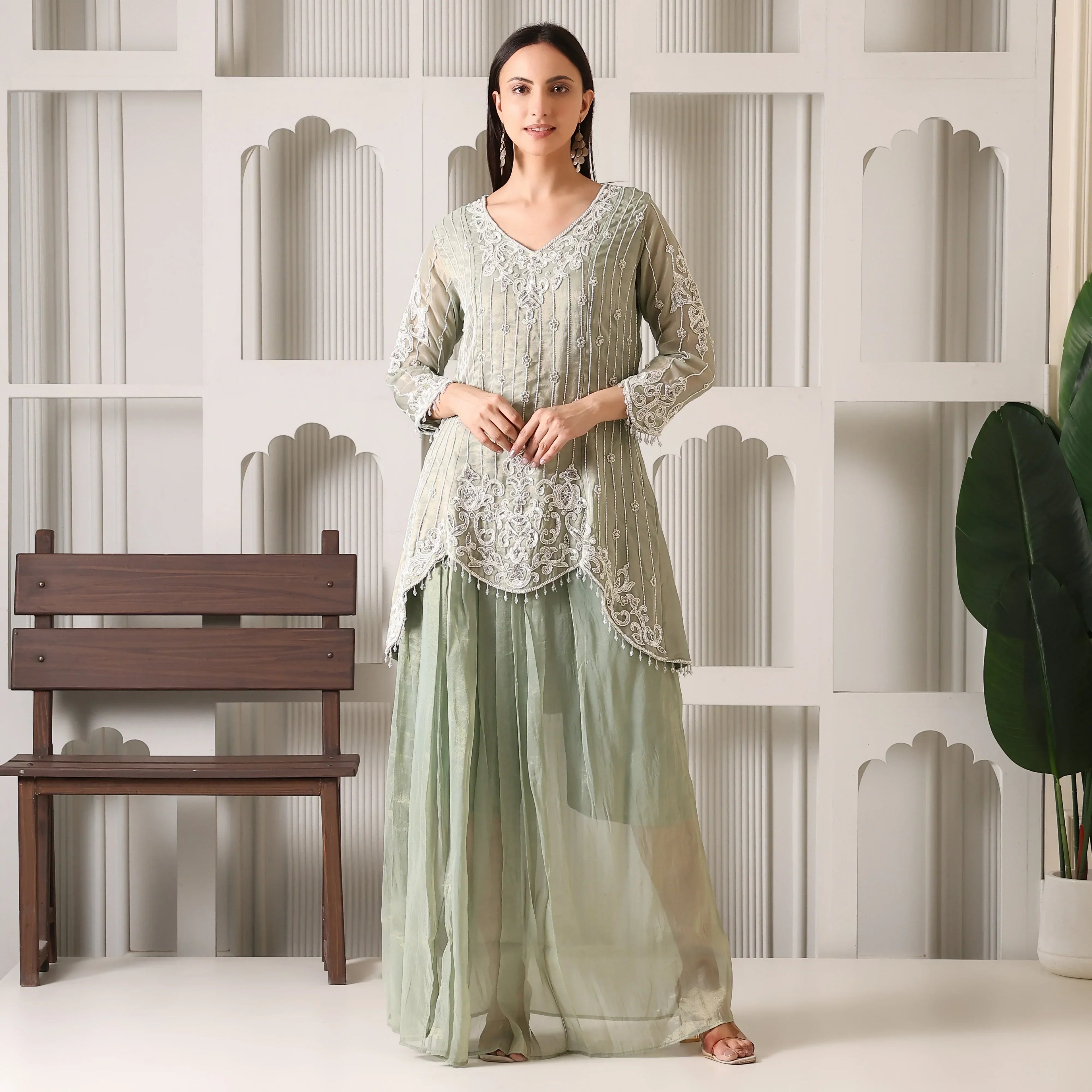 Woman in pastel green embroidered ethnic kurta and palazzo set, standing indoors