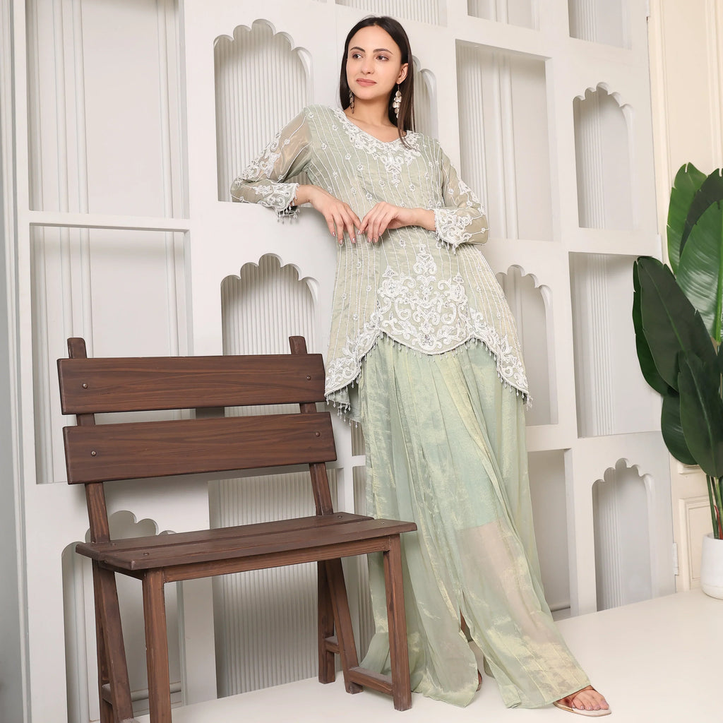 Woman in pastel green embroidered ethnic suit with palazzo pants, posing indoors