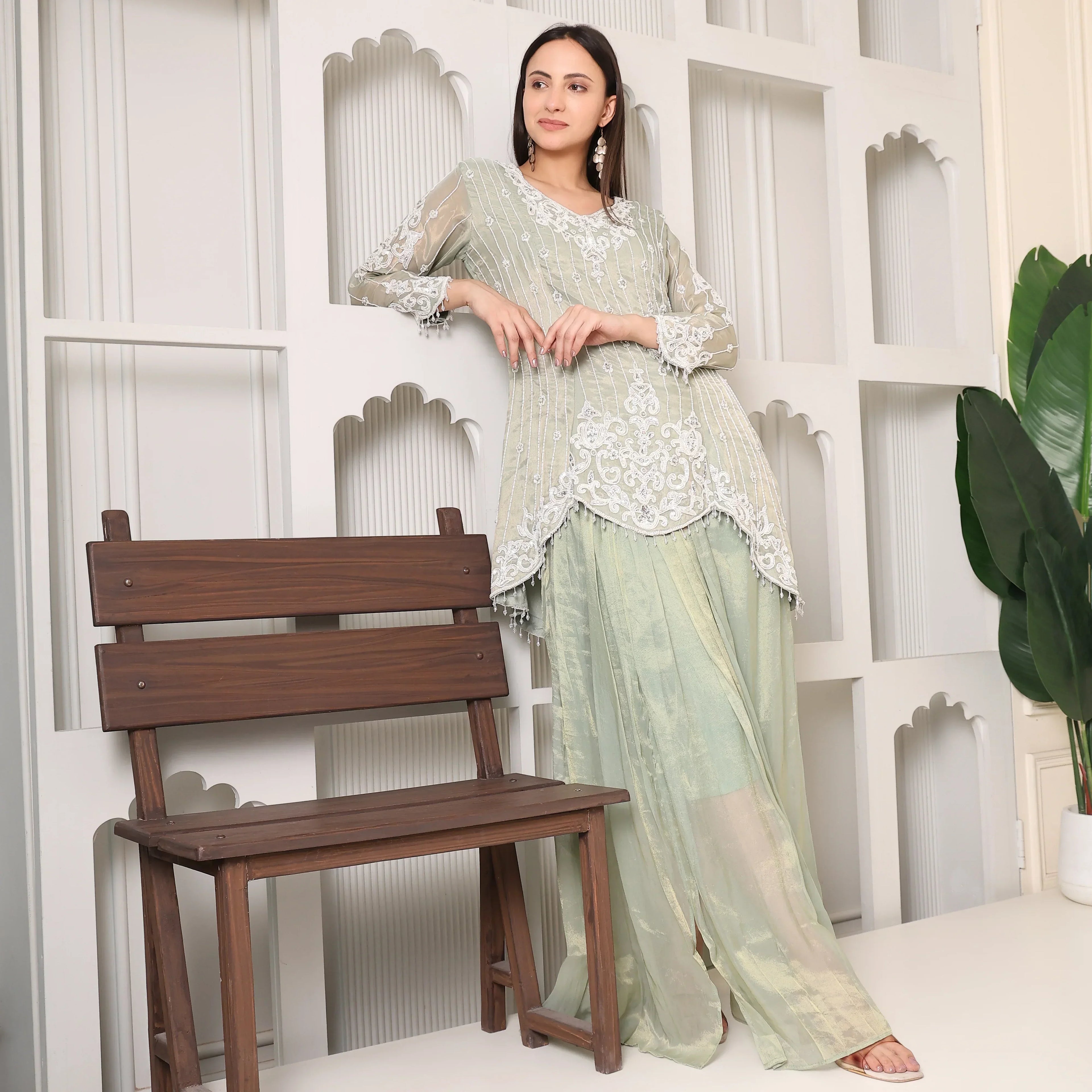 Woman in pastel green embroidered ethnic suit with palazzo pants, posing indoors