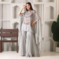 Woman in light grey embellished ethnic cape set with flared pants indoors