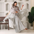 Woman in flowy pastel ethnic suit with embellished cape, wide-leg pants, festive occasion wear