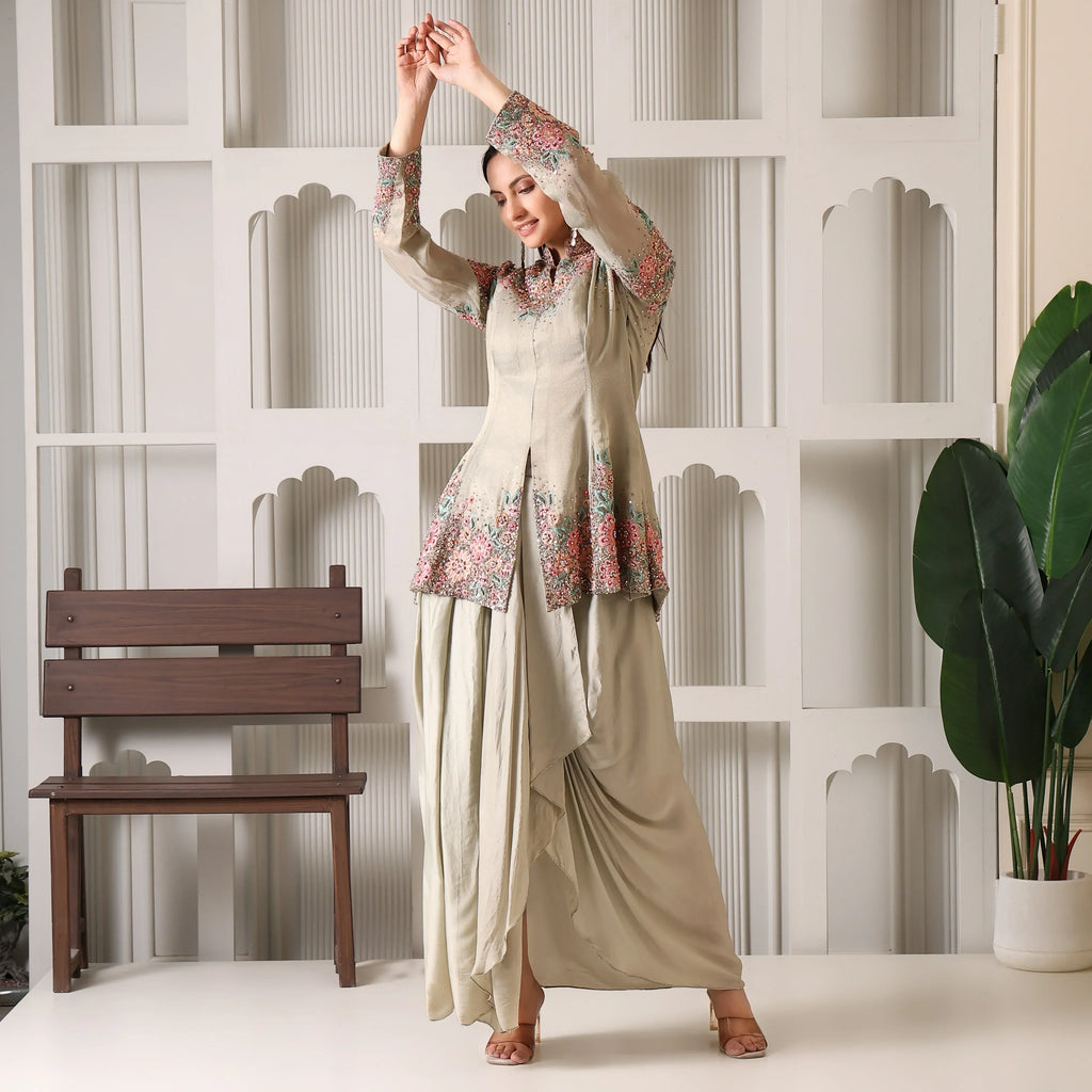 Woman wearing beige floral embroidered ethnic suit with draped pants, posing indoors