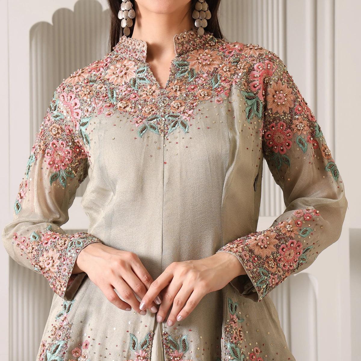 Woman wearing pastel embroidered ethnic suit with floral beadwork and long sleeves