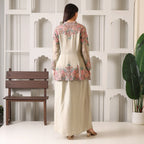 Woman in a beige ethnic long dress with floral embroidery, standing indoors