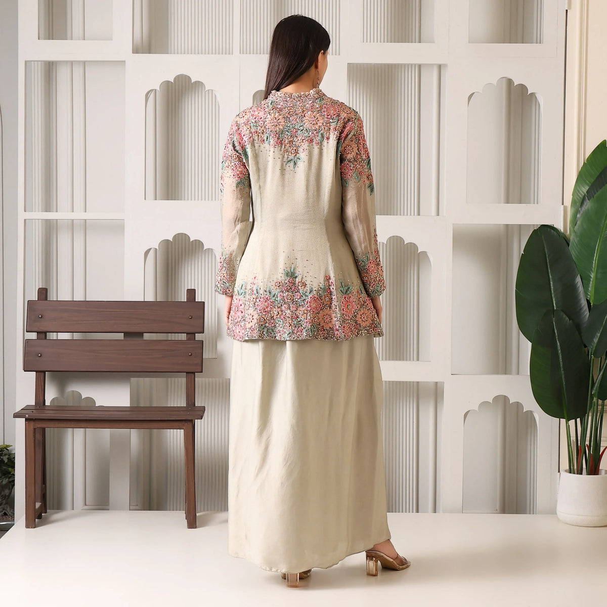 Woman in a beige ethnic long dress with floral embroidery, standing indoors