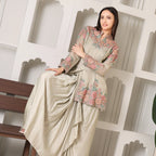 Woman wearing a pastel floral embroidered ethnic suit, draped dupatta, sitting indoors