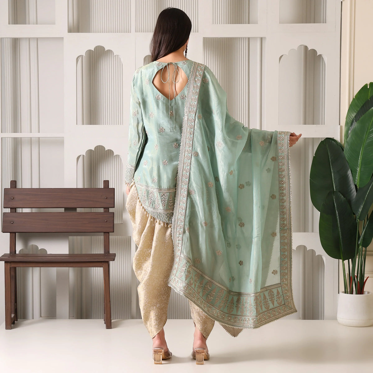 Woman in sage green embroidered ethnic suit with dupatta and beige pants, back view