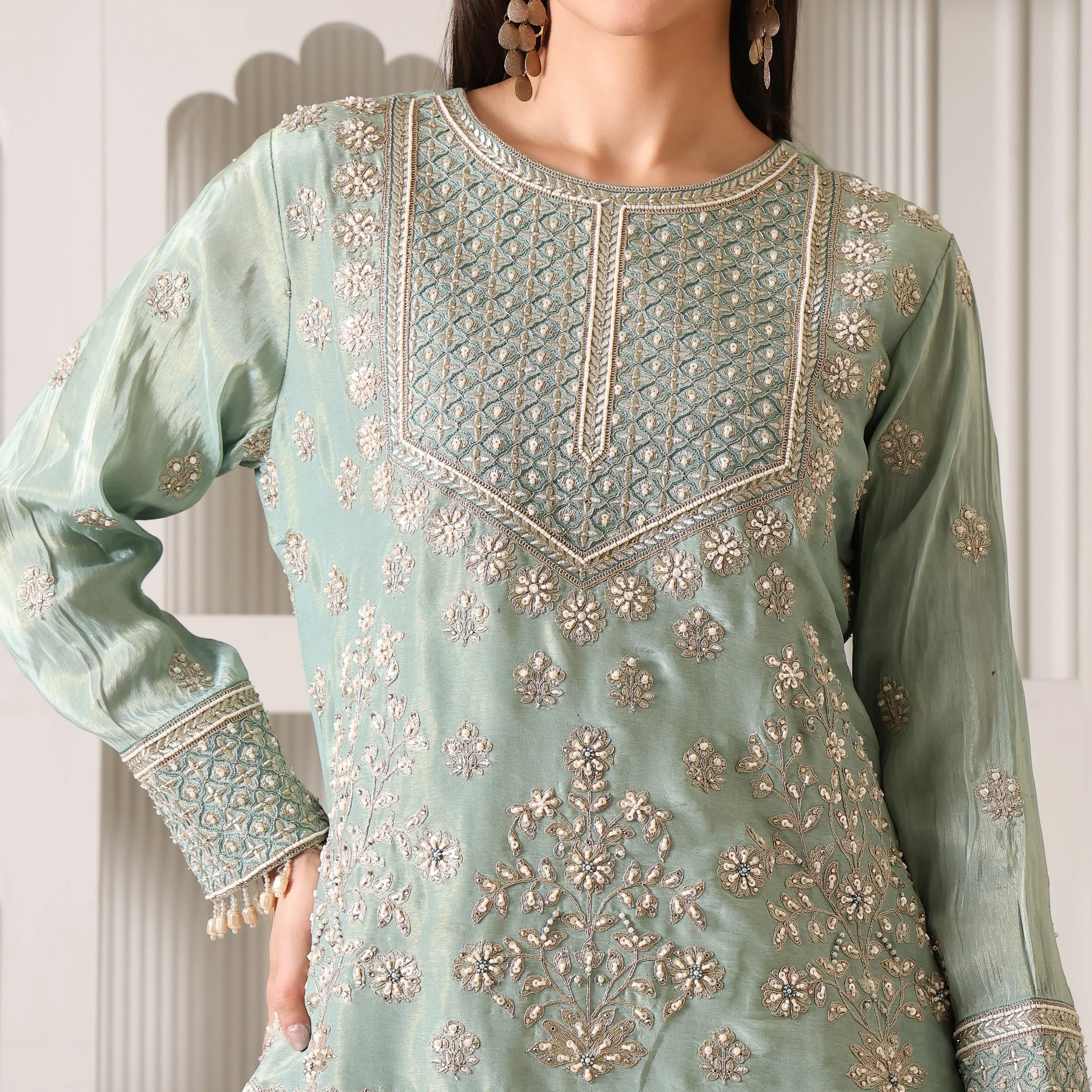 Close-up of woman wearing pastel green Banarasi Anarkali suit with intricate silver embroidery