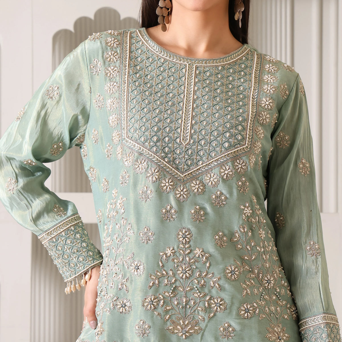 Close-up of woman wearing pastel green Banarasi Anarkali suit with intricate silver embroidery